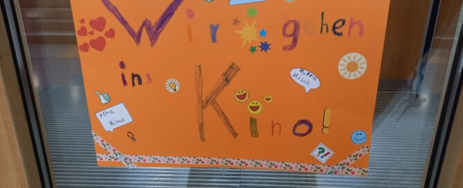 Zu sehen ist ein Plakat was Kinder gestaltet haben mit der Schrift: Wir gehen ins Kino